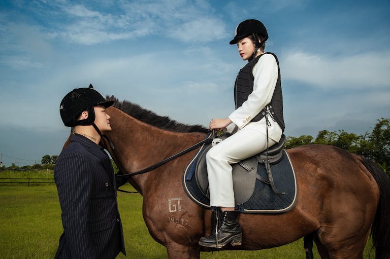 A person interacting with a horse and rider outdoors, showcasing equestrian elegance and style.
